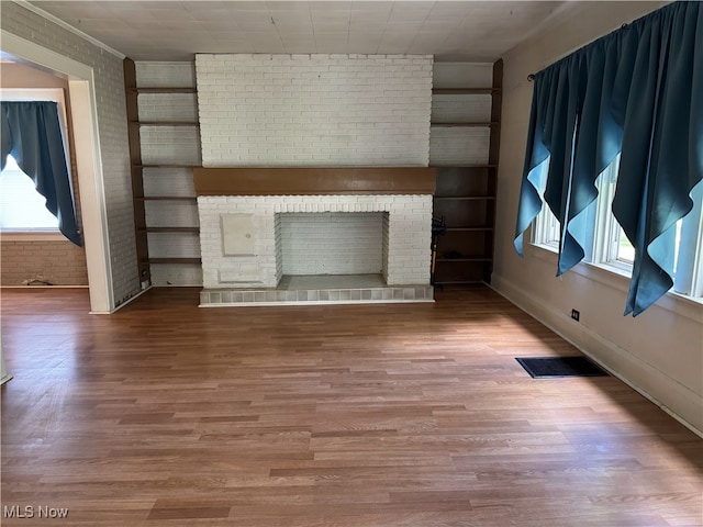 324 The Brooklands, Akron, OH 44305 - unfurnished living room featuring a fireplace, wood finished floors, brick wall, and baseboards