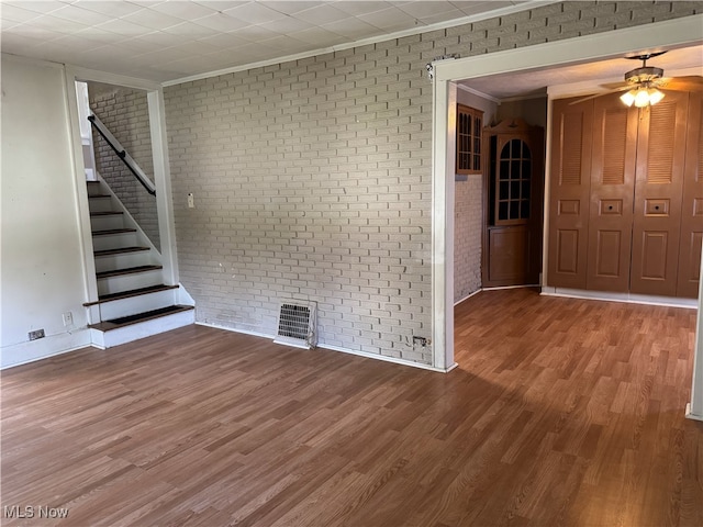 324 The Brooklands, Akron, OH 44305 - unfurnished living room featuring crown molding, brick wall, wood finished floors, a ceiling fan, and stairway