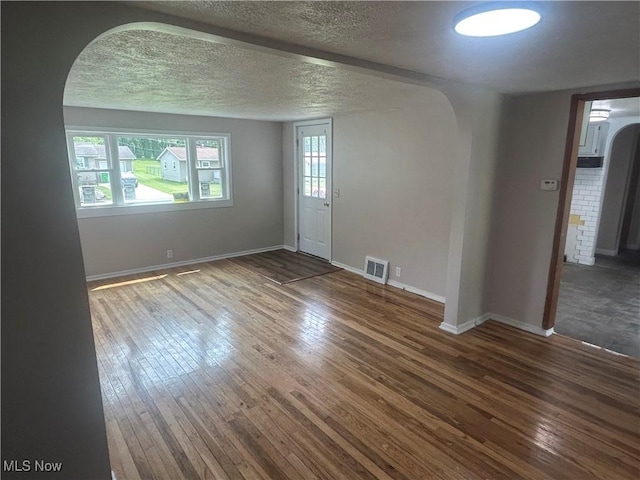 1706 Adams St, Coshocton, OH 43812 - empty room featuring arched walkways, wood-type flooring, baseboards, and a textured ceiling