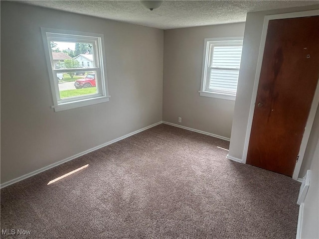 1706 Adams St, Coshocton, OH 43812 - unfurnished bedroom with carpet floors, a textured ceiling, multiple windows, and baseboards