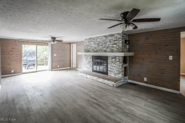 29655 Buck Rd, Salem, OH 44460 - unfurnished living room featuring a ceiling fan, wood walls, wood finished floors, baseboards, and a textured ceiling
