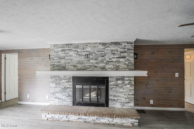 29655 Buck Rd, Salem, OH 44460 - detailed view of baseboards, wood finished floors, wooden walls, a stone fireplace, and a textured ceiling