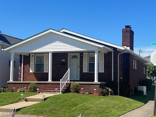 139 E Walnut St, Barnesville, OH 43713 - view of front facade featuring brick siding, a porch, a chimney, and a front lawn