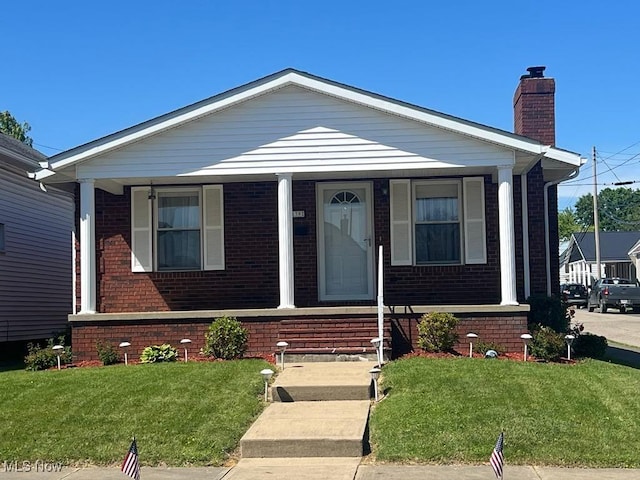 139 E Walnut St, Barnesville, OH 43713 - view of front of home with covered porch, brick siding, a chimney, and a front lawn