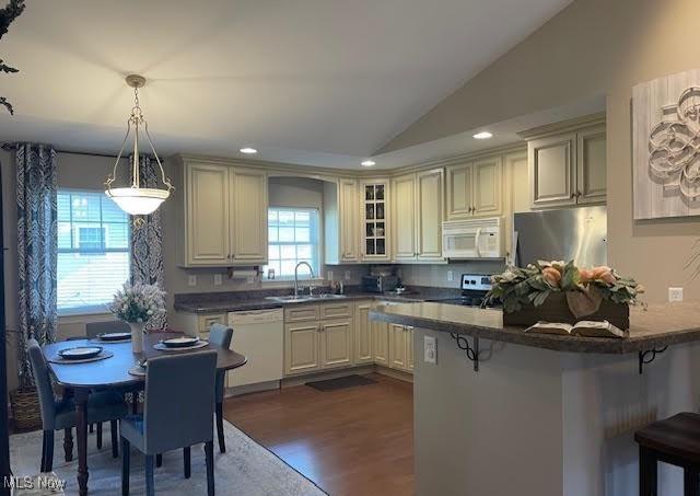 170 Sandy Ct Unit 11, New Middletown, OH 44442 - kitchen featuring white appliances, a sink, a kitchen bar, dark wood-style floors, and vaulted ceiling
