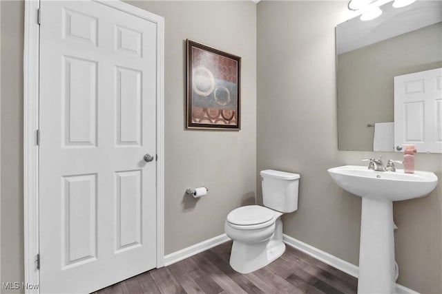 4527 Cupola Dr, Lorain, OH 44053 - half bathroom featuring toilet, baseboards, wood finished floors, and a sink