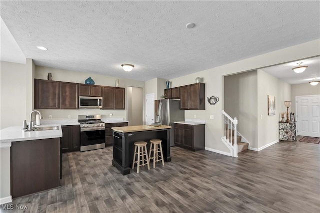 4527 Cupola Dr, Lorain, OH 44053 - kitchen featuring appliances with stainless steel finishes, a sink, dark wood-style floors, a kitchen breakfast bar, and light countertops