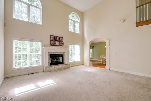 835 Thelma Dr, Wadsworth, OH 44281 - unfurnished living room featuring ornate columns, arched walkways, a towering ceiling, carpet flooring, and a tile fireplace