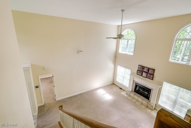 835 Thelma Dr, Wadsworth, OH 44281 - living area featuring a towering ceiling, ceiling fan, a tile fireplace, carpet flooring, and baseboards