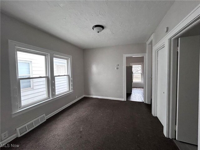 2920 E 111th St, Cleveland, OH 44104 - empty room featuring a textured ceiling, baseboards, and dark carpet