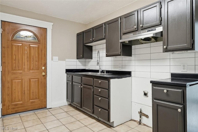 3399 E 65th St, Cleveland, OH 44127 - kitchen featuring under cabinet range hood, dark countertops, light tile patterned flooring, and decorative backsplash