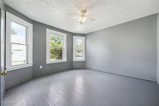 3399 E 65th St, Cleveland, OH 44127 - empty room with healthy amount of natural light, a textured ceiling, hardwood / wood-style floors, ceiling fan, and baseboards