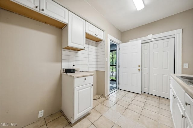 3399 E 65th St, Cleveland, OH 44127 - kitchen featuring tasteful backsplash, light countertops, light tile patterned flooring, white cabinetry, and a sink