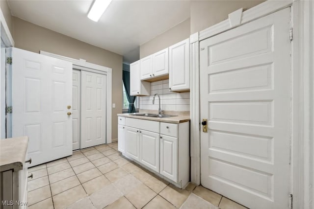 3399 E 65th St, Cleveland, OH 44127 - kitchen featuring a sink, white cabinets, light tile patterned floors, and tasteful backsplash