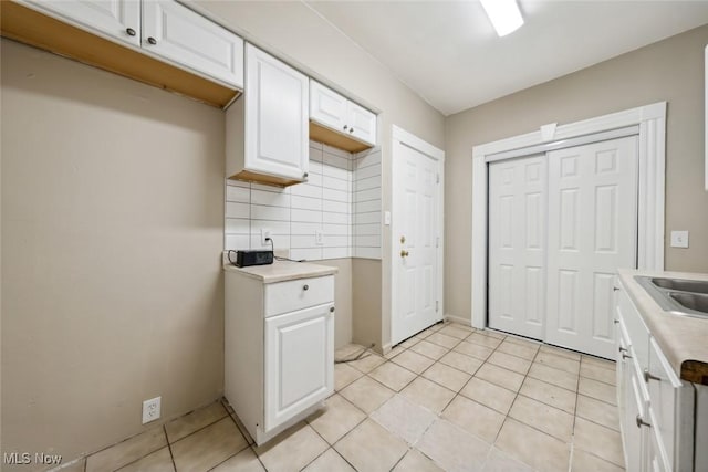 3399 E 65th St, Cleveland, OH 44127 - kitchen featuring decorative backsplash, light countertops, white cabinets, and light tile patterned flooring