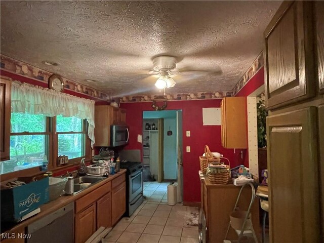 9439 Williams Rd, Diamond, OH 44412 - kitchen featuring appliances with stainless steel finishes, ceiling fan, light tile patterned flooring, a sink, and a textured ceiling