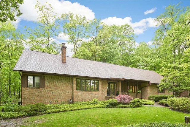 5074 Tall Timbers Dr, Richfield, OH 44286 - view of front of house with a chimney, a front yard, brick siding, and a shingled roof