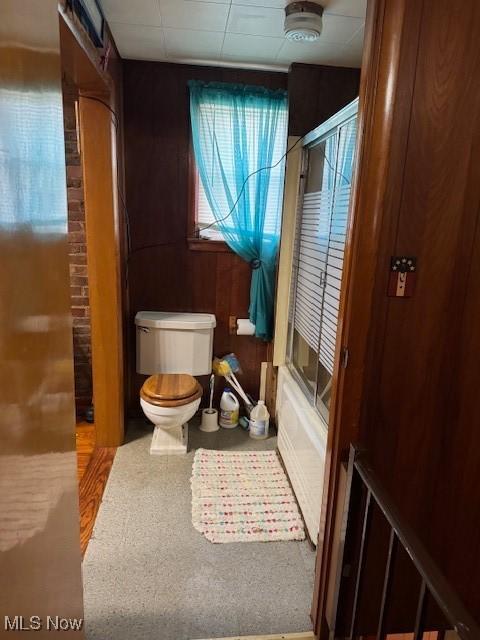 801 High St, Wellsburg, WV 26070 - bathroom featuring toilet, bath / shower combo with glass door, and wood walls