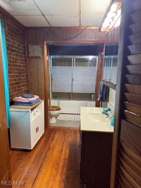 801 High St, Wellsburg, WV 26070 - full bathroom featuring vanity, wood finished floors, brick wall, toilet, and shower / bath combination