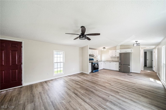 141 Marilyn Dr, Madison, OH 44057 - unfurnished living room with a textured ceiling, ceiling fan, light wood-style flooring, a sink, and baseboards