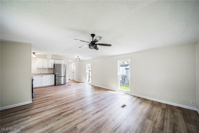 141 Marilyn Dr, Madison, OH 44057 - unfurnished living room featuring a ceiling fan, light wood finished floors, baseboards, a textured ceiling, and lofted ceiling