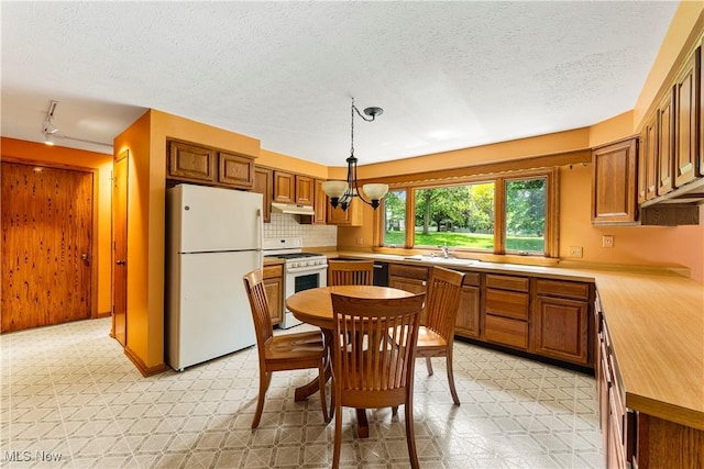 9852 Hocking St NW, Massillon, OH 44646 - kitchen with white appliances, light floors, under cabinet range hood, a sink, and a chandelier