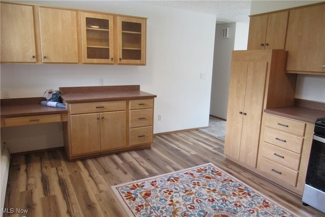 3318 Avon Blvd, Ashtabula, OH 44004 - kitchen with light brown cabinetry, light wood-style flooring, dark countertops, glass insert cabinets, and stainless steel gas stove