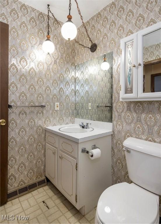 6533 Engle Rd, Brook Park, OH 44142 - half bathroom with wallpapered walls, vanity, toilet, and baseboards