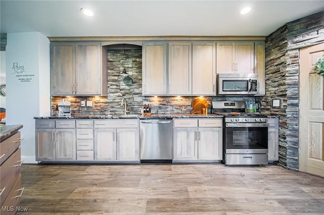 9012 Winesburg Rd, Dundee, OH 44624 - kitchen with appliances with stainless steel finishes, backsplash, a sink, dark stone counters, and light wood finished floors