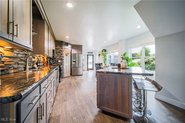 9012 Winesburg Rd, Dundee, OH 44624 - kitchen with stainless steel fridge, a sink, tasteful backsplash, a center island, and a kitchen bar