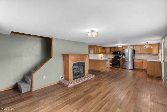 68290 Orchard Ave, Bridgeport, OH 43912 - unfurnished living room with dark wood finished floors, a sink, a brick fireplace, stairway, and baseboards