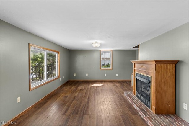 68290 Orchard Ave, Bridgeport, OH 43912 - unfurnished living room with a fireplace with raised hearth, healthy amount of natural light, dark wood-style flooring, and baseboards