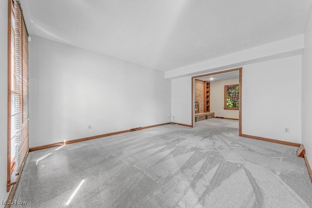 12935 Robinwood St NE, Alliance, OH 44601 - unfurnished room with baseboards, light carpet, and a fireplace