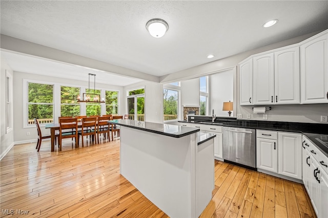 7776 Keystone Dr, Concord, OH 44077 - kitchen featuring stainless steel dishwasher, dark countertops, a sink, white cabinets, and a kitchen island