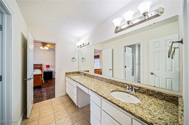 7776 Keystone Dr, Concord, OH 44077 - ensuite bathroom with double vanity, tile patterned floors, ceiling fan, baseboards, and a textured ceiling