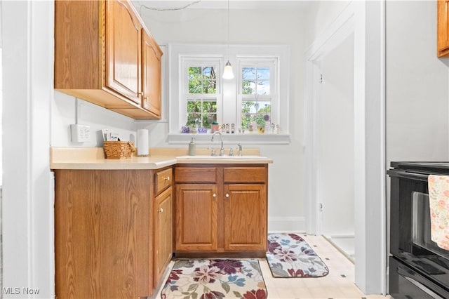 226 N 19th St, Sebring, OH 44672 - kitchen with a sink, range, light countertops, pendant lighting, and brown cabinetry