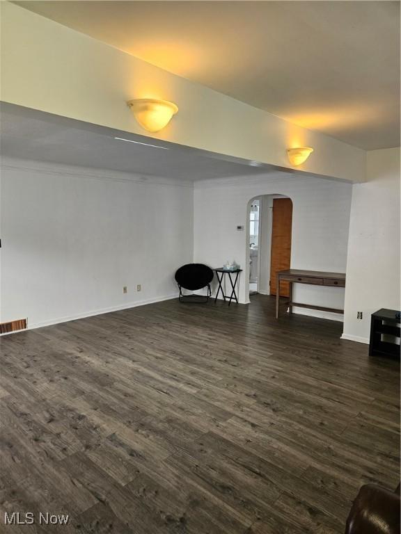 5102 Andrus Ave, North Olmsted, OH 44070 - unfurnished living room with arched walkways, dark wood finished floors, and baseboards