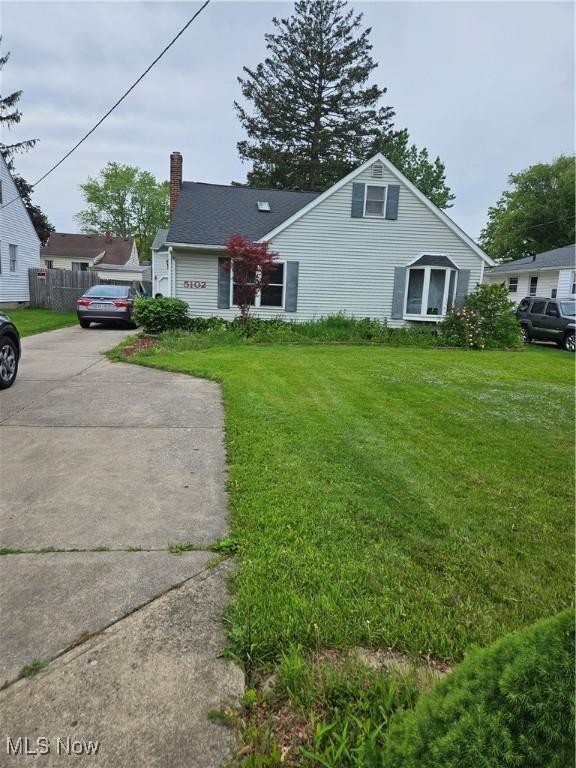 5102 Andrus Ave, North Olmsted, OH 44070 - view of front facade featuring a chimney, a front yard, and concrete driveway