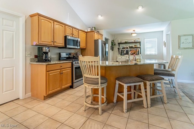 8121 Hitchcock Rd Unit 1, Youngstown, OH 44512 - kitchen with stainless steel appliances, a breakfast bar area, light tile patterned floors, an island with sink, and light stone countertops