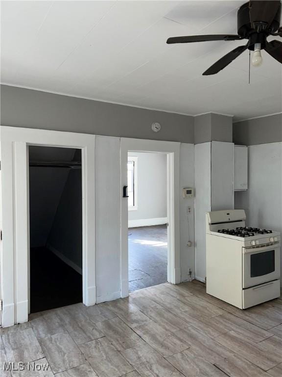 6701 Gertrude Ave, Cleveland, OH 44105 - kitchen featuring white gas stove, light wood-type flooring, ceiling fan, and white cabinetry