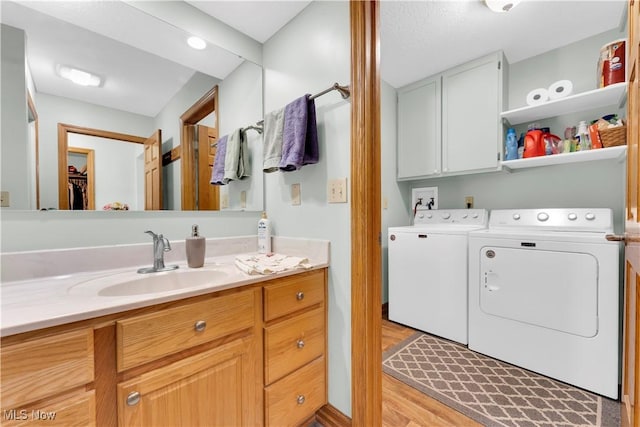 9903 Vermilion Rd, Amherst, OH 44001 - bathroom with washing machine and dryer, vanity, wood finished floors, and a walk in closet