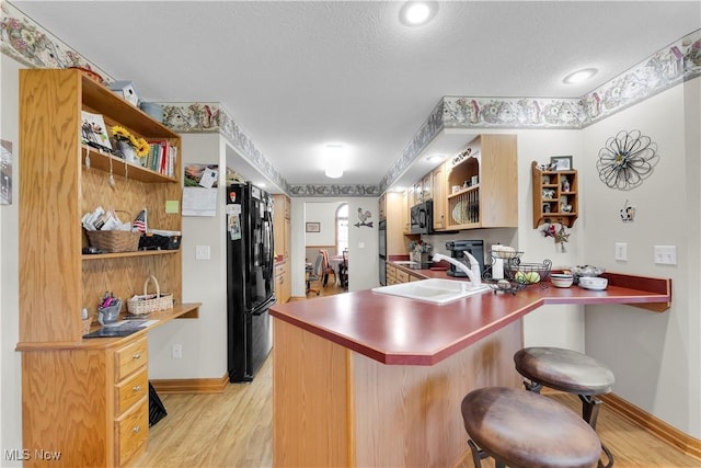 9903 Vermilion Rd, Amherst, OH 44001 - kitchen with open shelves, black appliances, light wood-style floors, a peninsula, and a textured ceiling