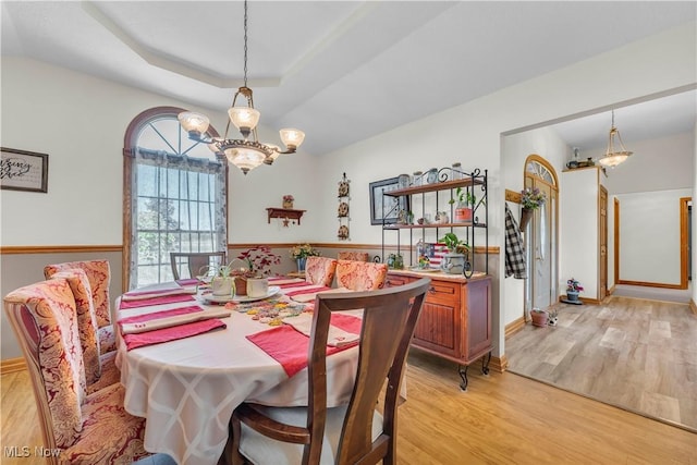 9903 Vermilion Rd, Amherst, OH 44001 - dining room featuring light wood-style floors, a chandelier, a raised ceiling, and baseboards