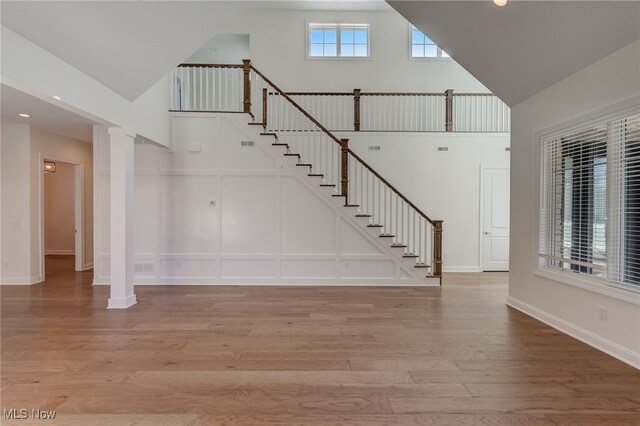 2540 Edgewood Trce, Pepper Pike, OH 44124 - unfurnished living room featuring high vaulted ceiling, light wood-style floors, stairs, baseboards, and decorative columns