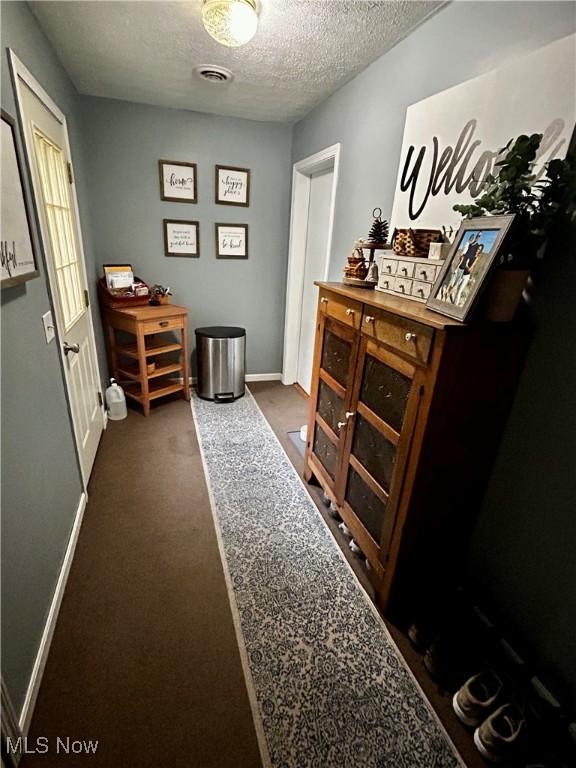 645 Arends Ridge Rd, Marietta, OH 45750 - hall featuring a textured ceiling, baseboards, and dark colored carpet