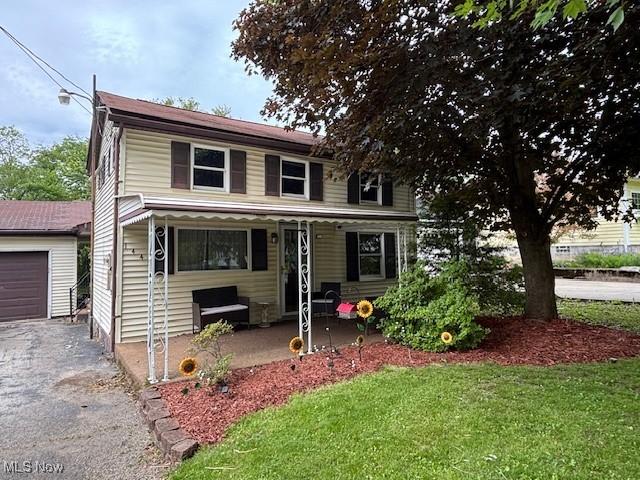 1445 E County Line Rd, Mineral Ridge, OH 44440 - view of front of home with a porch, asphalt driveway, a front yard, and a garage