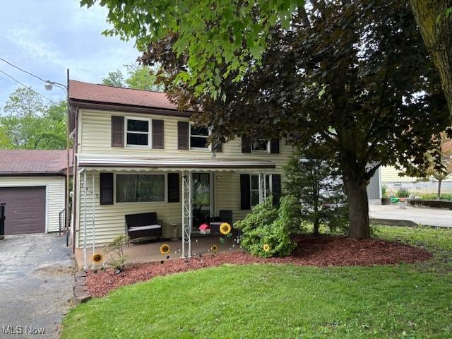 1445 E County Line Rd, Mineral Ridge, OH 44440 - view of front of house featuring driveway, a front yard, an attached garage, and covered porch