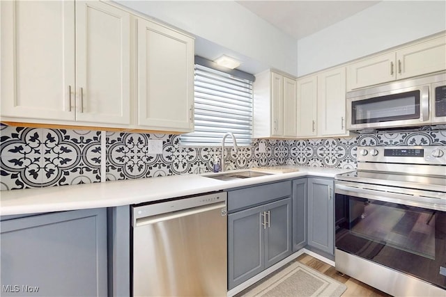226 Cunningham Ln, Steubenville, OH 43952 - kitchen with stainless steel appliances, a sink, light countertops, gray cabinetry, and decorative backsplash
