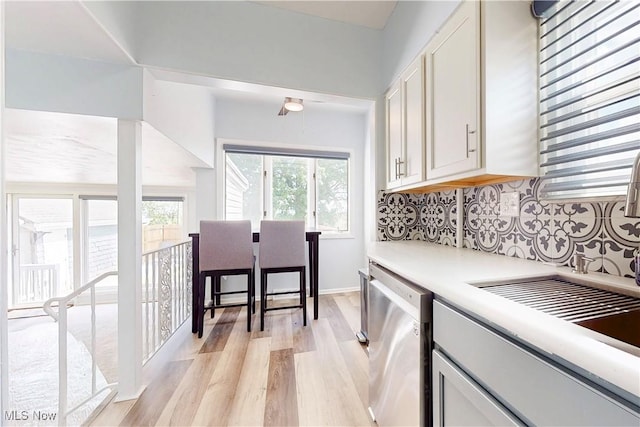 226 Cunningham Ln, Steubenville, OH 43952 - kitchen featuring stainless steel dishwasher, light wood finished floors, light countertops, decorative backsplash, and white cabinetry