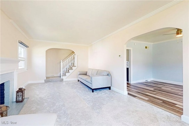 226 Cunningham Ln, Steubenville, OH 43952 - carpeted living area featuring arched walkways, crown molding, baseboards, a fireplace with flush hearth, and stairway